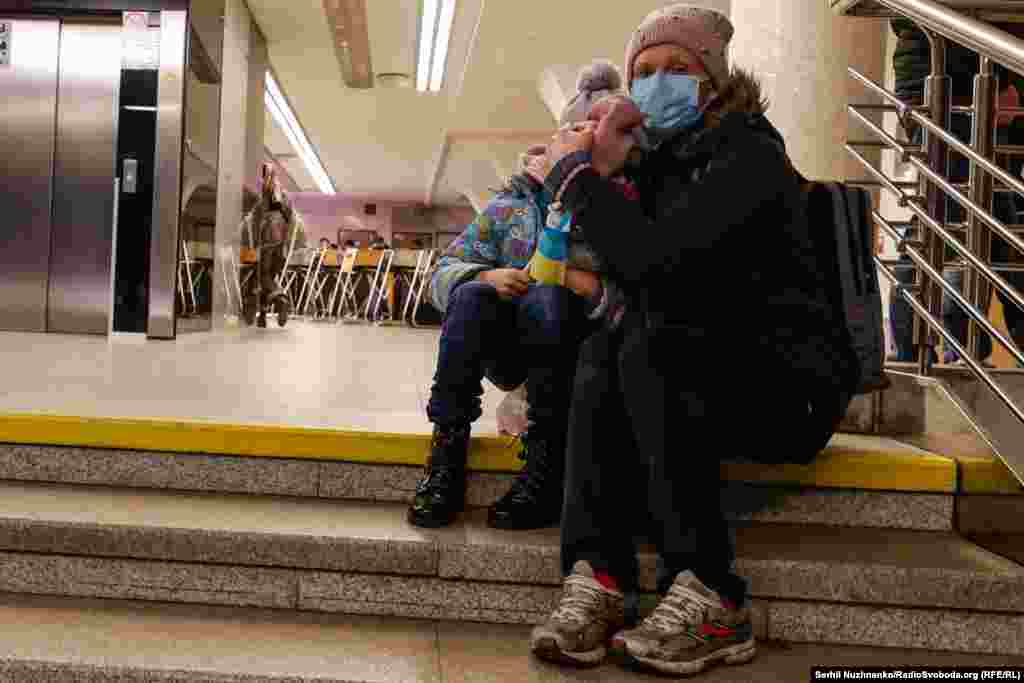 Жінка обіймає дитину, ховаючись від можливих обстрілів на станції метро «Голосіївська», Київ, 24 лютого 2022 року.Перші години війни, одні люди ще звично їдуть у метро у справах, а інші вже поспішають із валізами виїхати з міста