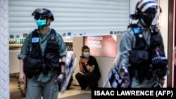 Hong Kongda polisiýa barlag operasiýasyny geçirýän mahaly, dükan satyjysy garaşýar. 28-nji iýun, 2020 ý.