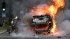 Пожарникар гасне запален автомобил во париското предградие Нантер, 29 јуни 2023 година.