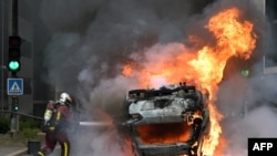 Vatrogasac gasi zapaljeni automobil u pariškom predgrađu Nanterre, 29. juna 2023.