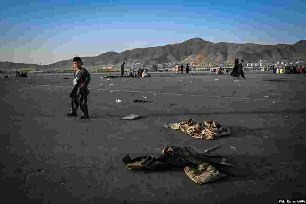 A child walks near discarded Afghan military uniforms as his family waits to leave Kabul airport on August 16.