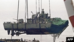 A floating crane lifts the stern of the South Korean warship to place it on a barge during recovery operations in mid-April, nearly three weeks after it sank.