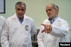 Mohammad Eslami (left), the head of the Iranian Atomic Energy Organization, speaks with Iranian President Masoud Pezeshkian in Tehran. (file photo)