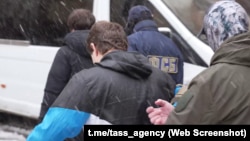 Captură de pe un video publicat de FSB și distribuit de agenția de știri TASS în care ar apărea cei doi moldoveni escortați de ofițeri ruși.