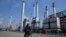FILE - In this Dec. 22, 2014 file photo, an Iranian oil worker rides his bicycle at the Tehran oil refinery