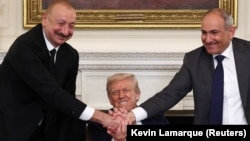 U.S. President Donald Trump holds the hands of Azerbaijan's President Ilham Aliyev and Armenia's Prime Minister Nikol Pashinian as they shake hands between each other during a trilateral signing event at the White House, in Washington, August 8, 2025.
