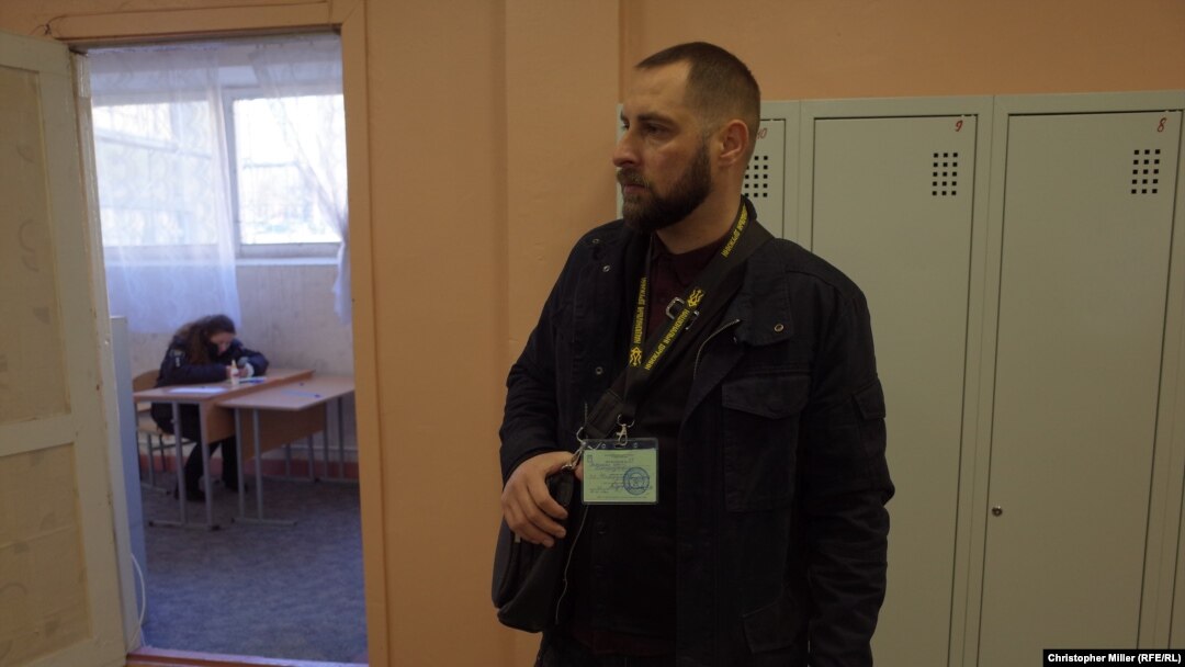 Yuriy Petrenko, a member of the National Militia, monitors voting at School No.14 in Podil, in Kyiv, on March 31.
