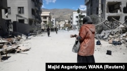 A woman stands on a road in a residential neighborhood damaged by a strike amid the US-Israeli conflict with Iran, in the capital Tehran.
