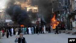 Shi'ite Muslims gather near burning shops at a market following clashes during an Ashura procession in Rawalpindi on November 15.