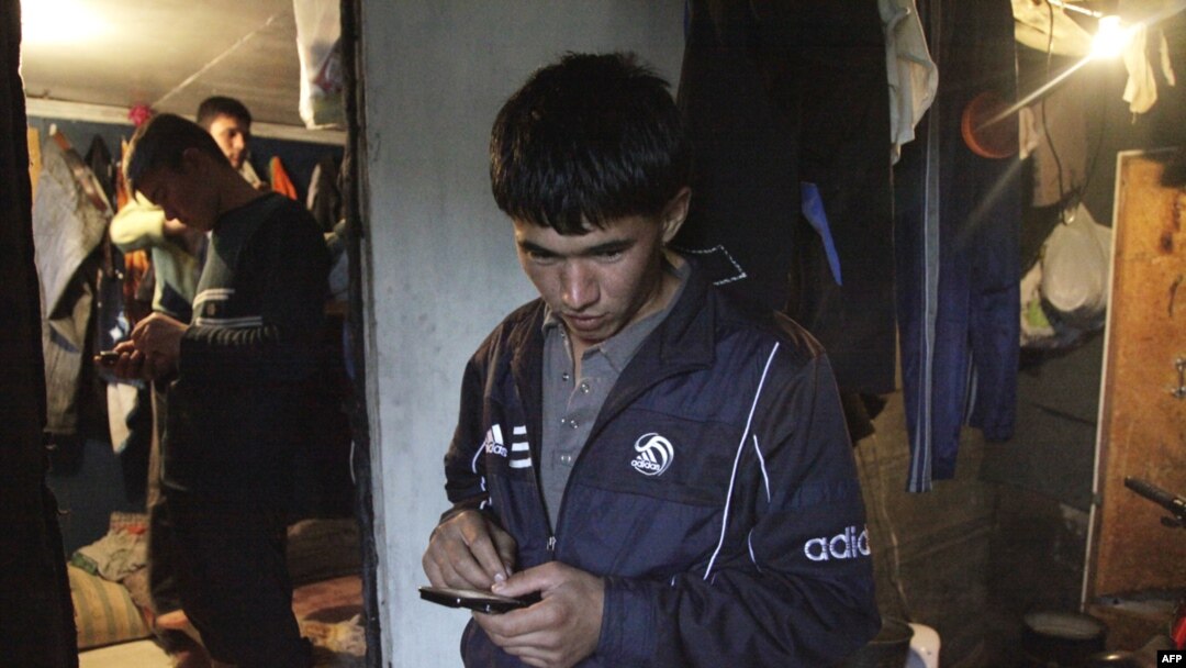 A Tajik migrant worker sends a message on his mobile phone, Moscow.