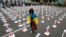 A grieving woman wears the Ukrainian flag as she walks among white crosses with portraits of dead Ukrainian soldiers in front of the Russian Embassy in Kyiv in August.