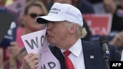 U.S. -- Republican presidential nominee Donald Trump kisses a "Women for Trump" placard during a rally at the Lakeland Linder Regional Airport in Lakeland, Florida, October 12, 2016