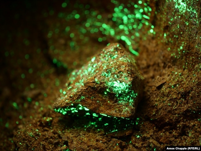 Скали, осеяни с радиоактивен отунит, в изоставена съветска уранова мина. Минералът свети под UV фенерче, използвано за идентифициране на радиоактивни находища.