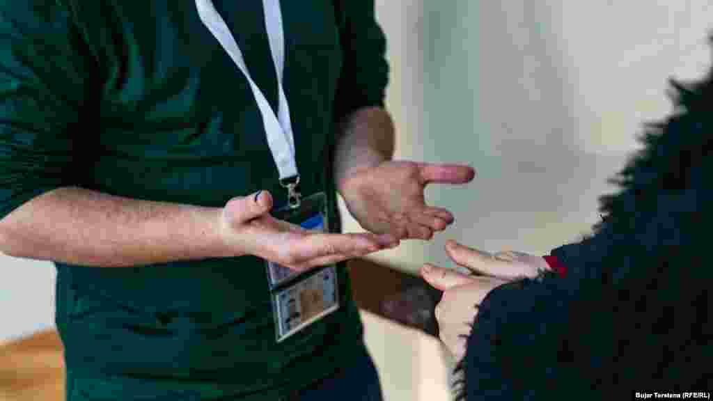 Një grua ia tregon gishtat e mëdhënj të duarve një komisionari zgjedhor teksa përgatitet të hyjë për të votuar në zgjedhjet parlamentare të 9 shkurtit 2025, në Prishtinë.Ato zgjedhje nuk dhanë fitues absolut, duke e zhytur vendin në krizë institucionale dhe duke nxitur zgjedhje të parakohshme parlamentare në fundvit.