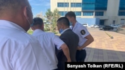 Сотрудники службы безопасности пытаются вывести протестующего за территорию компании. Нур-Султан, 8 июня 2021 года.