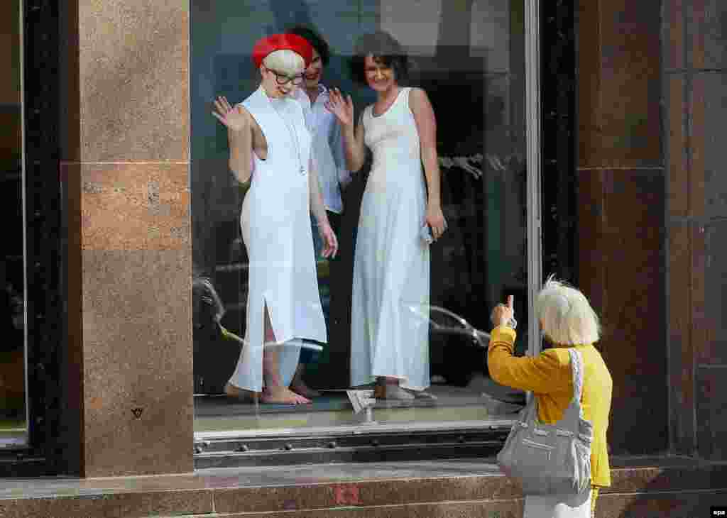 A woman gives a thumbs up to women posing in a shop window of a shopping mall in downtown Kyiv. (epa/Serhiy Dolzhenko)