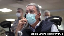 TURKEY -- Turkish Defense Minister Hulusi Akar, right, and Chief of Staff Gen. Yasar Guler wearing face masks to protect against the coronavirus, monitor the operation at a military headquarters in Ankara, June 15, 2020