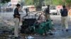 Police officials stand beside a mangled auto-rickshaw at the site of a suicide bomb attack in Peshawar.