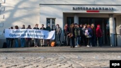 Луѓе држат транспарент за солидарност со жртвите од Аушвиц пред објектот каде се одвива судењето на Гроенинг. 