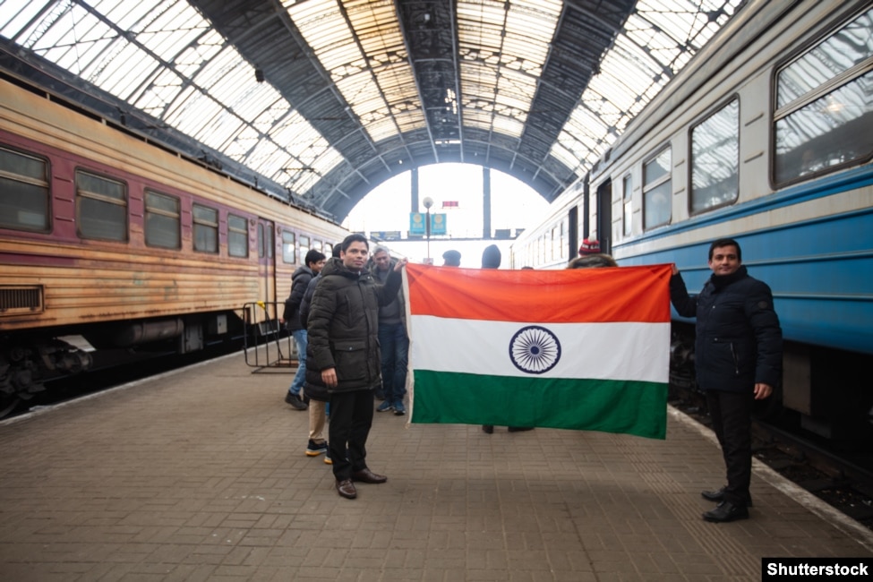 Dy punëtorë indianë mbajnë në duar flamurin e shtetit të tyre në Lviv në mars të vitit 2022 para se të largohen nga Ukraina. Para nisjes së pushtimit rus të Ukrainës më 2022, afër 22.000 punëtorë të huaj ishin të regjistruar në Ukrainë.