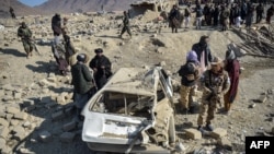 Taliban security personnel inspect a damaged car two days after air strikes by Pakistan in the Barmal district of eastern Paktika Province on December. 