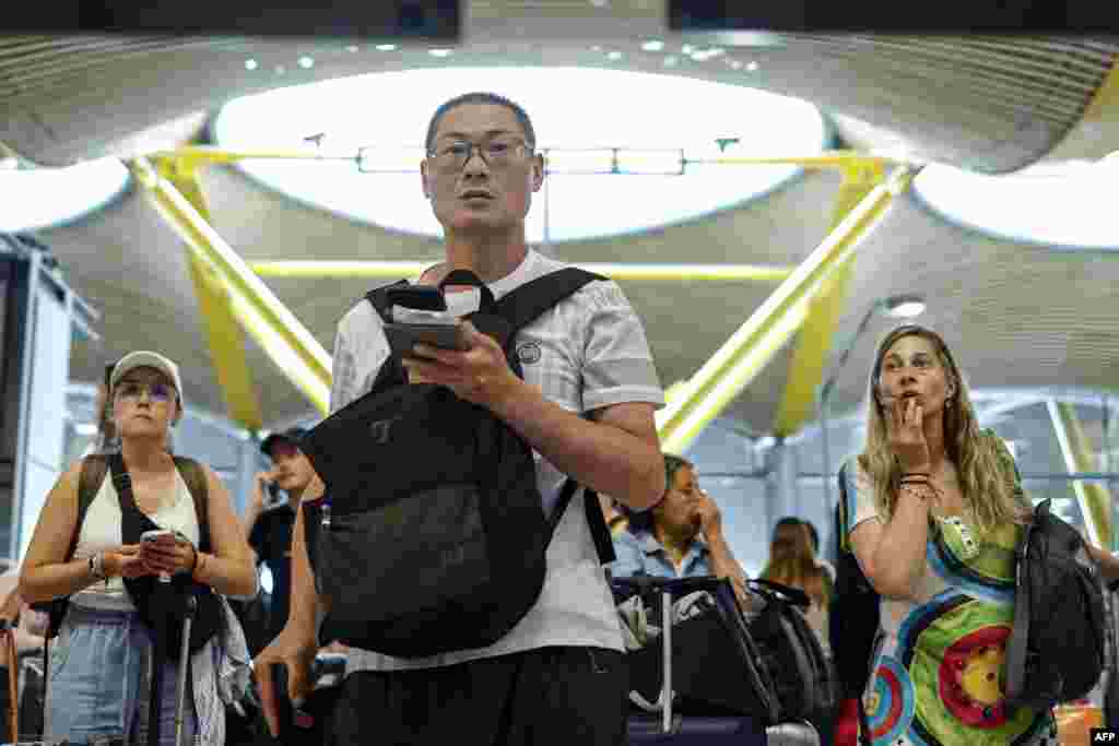 Passengers wait for new information at the flight information boards at Terminal 4 of Adolfo Suarez Madrid-Barajas Airport.