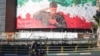 Iranians ride a motorbike past a huge banner of former IRGC commander Qasem Soleimani in Tehran in December.