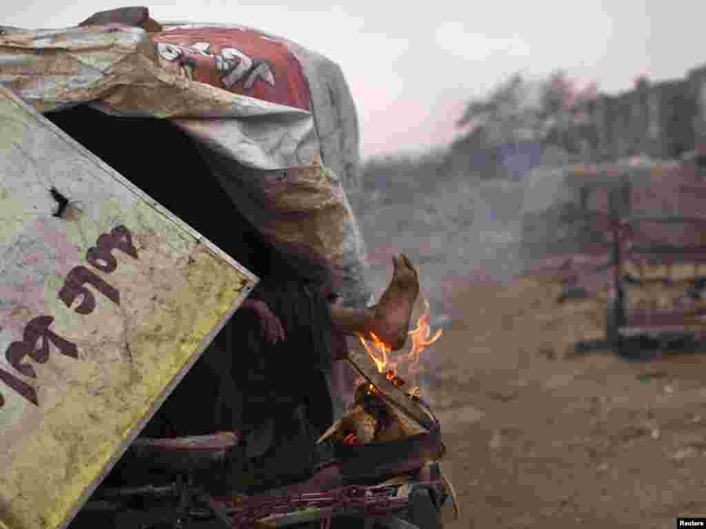 A homeless man warms his foot on a fire in Kabul January 20. Photo by Ahmad Masud for Reuters