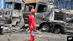 Spasilac stoji ispred spaljenih vozila nakon što su velika eksplozija i požar potresli luku Šahid Radžei u blizini južnog lučkog grada Bandar Abas u Iranu, 26. aprila.