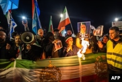 Демонстранты держат иранские флаги и плакаты, использовавшиеся до Исламской революции 1979 года, во время протестного марша в знак солидарности с Ираном. Нидерланды, Амстердам, 14 января 2026 года