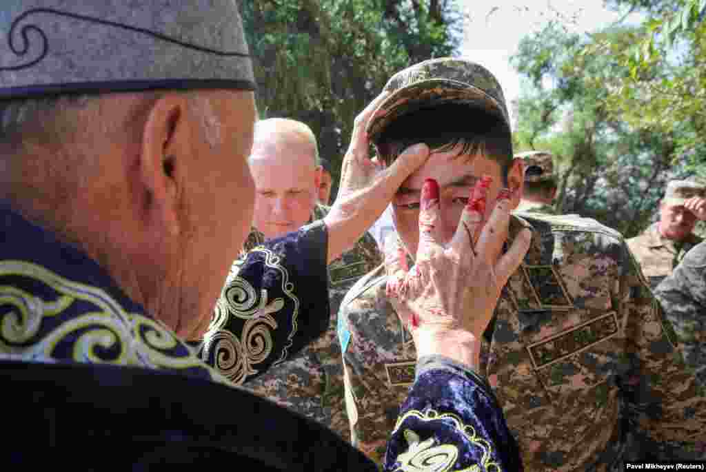 A Muslim cleric puts a blood mark on the forehead of an army serviceman in the village of Uzynagash outside Almaty, Kazakhstan.