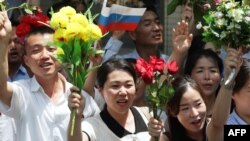 Pxenyanda insanlar Şimali Koreya lideri Kim Çen In və Rusiya prezidenti Vladimir Putini daşıyan kortejə əl yelləyirlər.