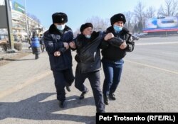 Полицейлер егде жастағы адамды қос қолтығынан алып, көлікке қарай сүйрелей жөнелді. Алматы, 10 қаңтар 2021 жыл.