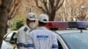 Emergency first responders wearing protective masks stand along a street in Tehran, February 24, 2020