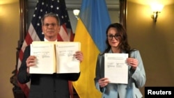 Ministrul american de finanțe, Scott Bessent, și prim-viceprim-ministra ucraineană, Iulia Sviridenko, demonstrând acordul privind mineralele semnat de ei la Washington, pe 30 aprilie 2025