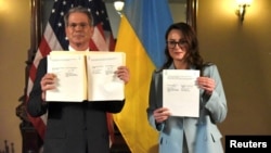 U.S. Treasury Secretary Scott Bessent (left) and Ukrainian First Deputy Prime Minister Svyrydenko pose for photographers, showing the minerals deal they signed in Washington on April 30.