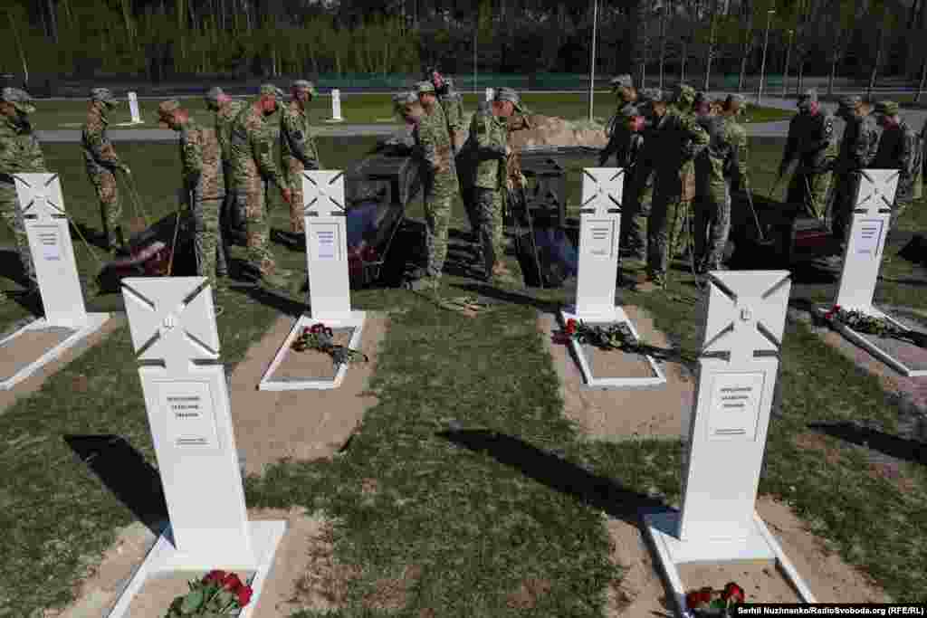 Труни невідомих загиблих українських захисників опускають у могили