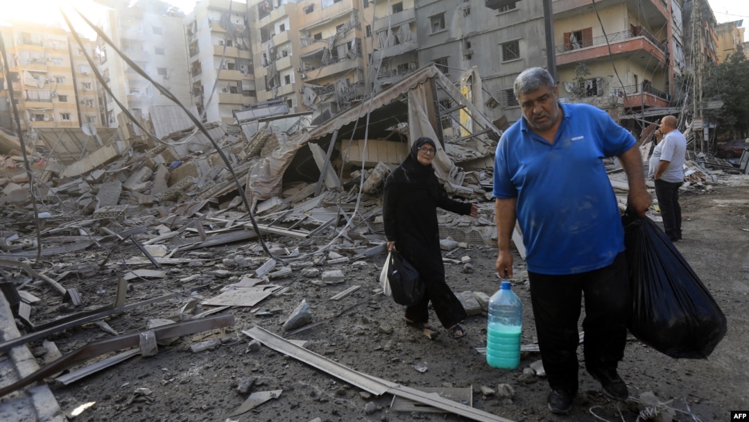 Residents carry some belongings as they walk amid the aftermath of an Israeli strike that targeted the Sfeir neighborhood in Beirut’s southern suburbs on October 6.