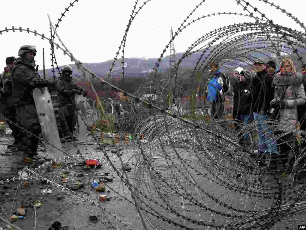 Ethnic Serbs stand by a barbed-wire barricade erected by KFOR soldiers at a roadblock near the village of Jagnjenica in northern Kosovo on December 6 (Photo for AFP by Sasa Djordjevic) 