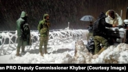 مرستندويه ډلې د جنورۍ پر پر ۲۲مه ناوخته په تيرا کې د کډوالو پر مخ بندې شوې لارې له واورو پاکوي. 