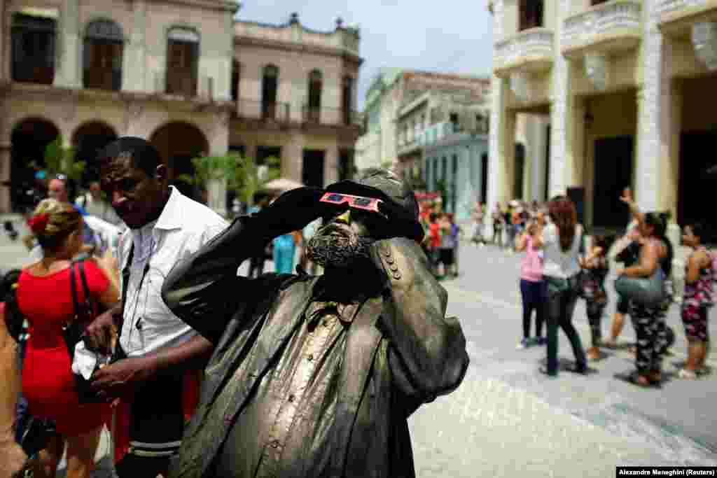 A street performer looks towards the sky as enthusiasts gather in Old Havana for the partial solar eclipse in Cuba on August 21. (Reuters/Alexandre Meneghini)