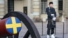 یک سرباز سوئدی در محوطه کاخ سلطنتی این کشور در کنار یک توپ نمایشی نگهبانی می‌دهد