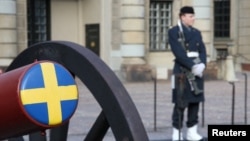 یک سرباز سوئدی در محوطه کاخ سلطنتی این کشور در کنار یک توپ نمایشی نگهبانی می‌دهد