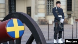 Un soldat stă de pază lângă un tun ceremonial în curtea Palatului Regal din Stockholm, capitala Suediei.