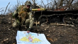 Украинский военнослужащий показывает фотографу российскую стенгазету рядом со сожженным российским танком возле села Мала Рогань к востоку от Харькова, 1 апреля 2022 года.