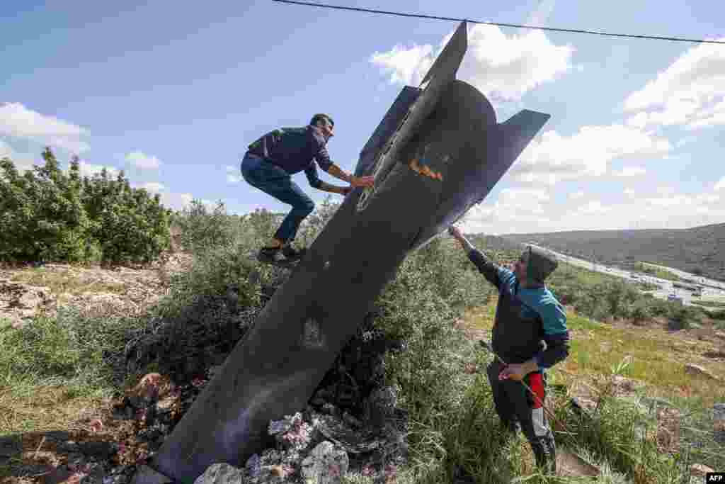 A Palestinian man scales Iranian missile debris that landed in the Israeli-occupied West Bank on March 24.