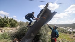 A Palestinian man scales Iranian missile debris that landed in the Israeli-occupied West Bank on March 24.