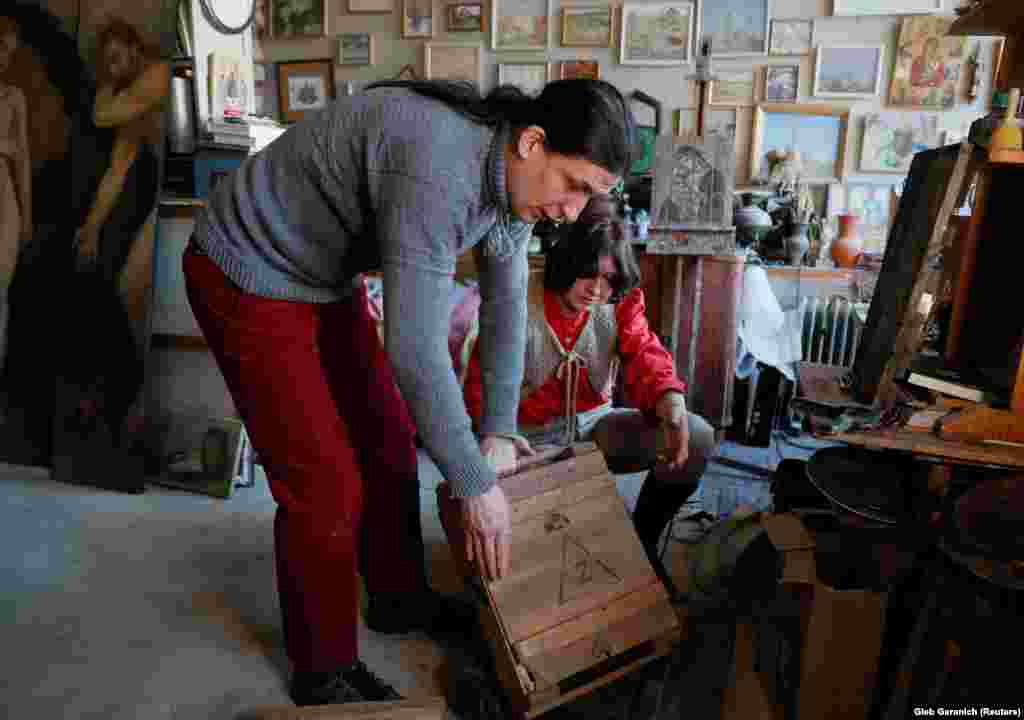 Instead of using regular wooden panels, Klymenko and his wife, Sofia Atlantova (right), paint Christian icons on the lids and bottoms of the ammo boxes.