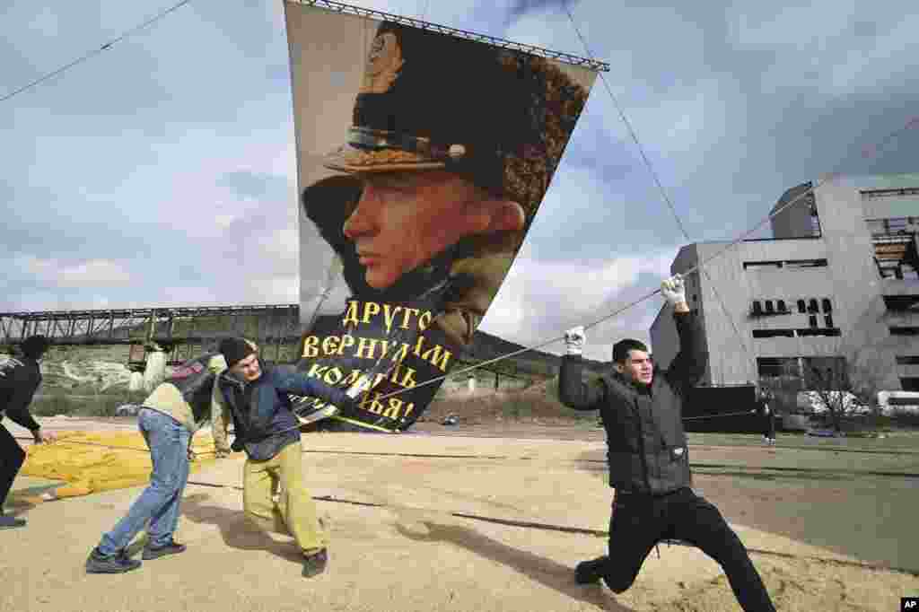 Enthusiasts fix a portrait of Russian President Vladimir Putin to a balloon during a celebration of the anniversary of Crimea&#39;s annexation from Ukraine in 2014 in Sevastopol on March 18. (AP)