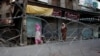 Kashmiri women walk past concertina wire laid across a road during restrictions after the scrapping of the special constitutional status for Kashmir by the Indian government in Srinagar on August 20. 